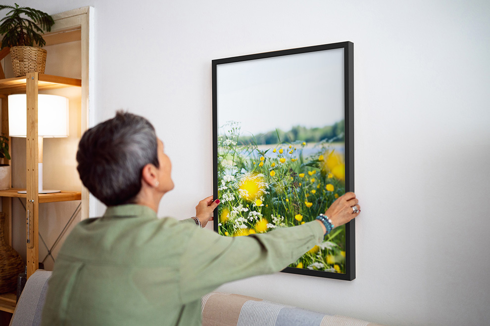 Appendere un poster al muro: una donna appende un poster incorniciato. Appendere un poster al muro: una donna appende un poster incorniciato.